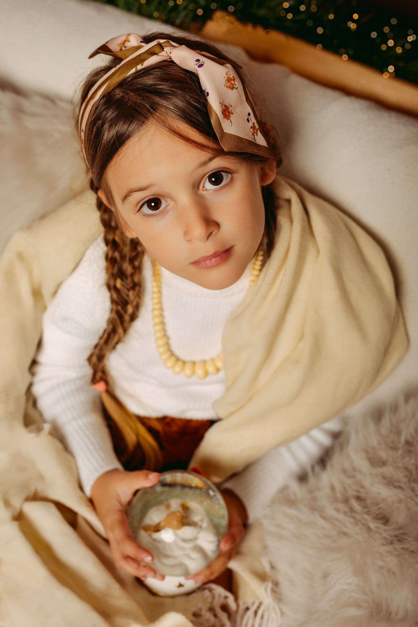 A beautiful portrait of a young girl holding a snow globe, captured during a magical and cozy Christmas mini session in Dorchester.