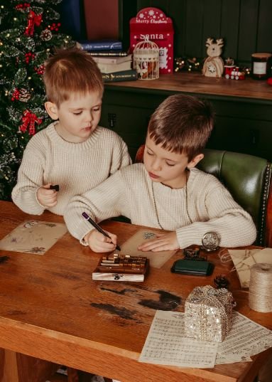 Two brothers writing a letter to Santa during their classic Christmas mini session, showcasing the beautiful results clients receive at Sandi Studio in Dorchester.
